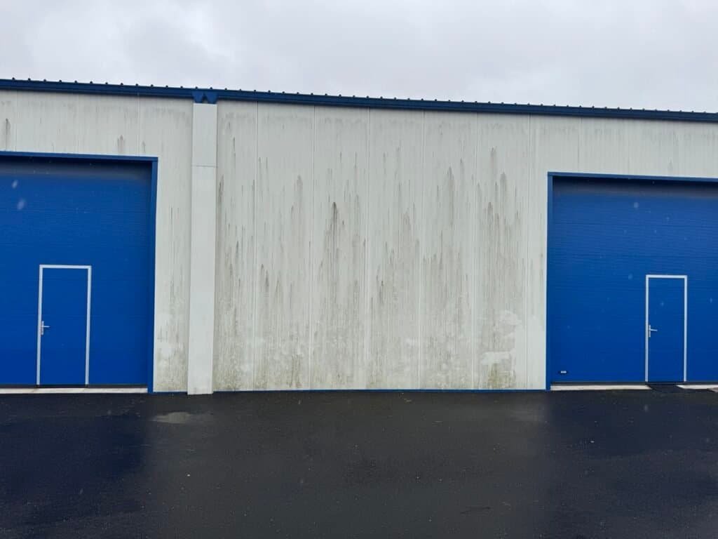 Bardage bac acier blanc marqué de coulures sur un bâtiment d’activité à Libourne