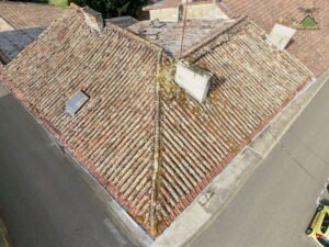Vue par drone d'une toiture ancienne en tuiles canal couverte de mousses et de lichens