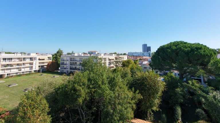 Vue aérienne par drone d'une résidence en copropriété : immeubles à toits-terrasses, balcons, pelouse et parc arboré