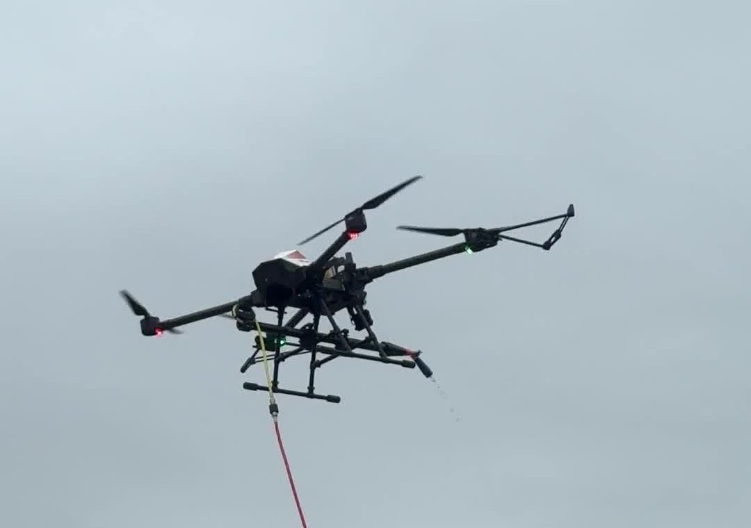 Drone de pulvérisation Eco Drones en vol lors d'un traitement de toiture, buse en action et tuyau d'alimentation