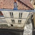 Vue aérienne par drone d’une façade en pierre de taille, de sa toiture en tuiles canal et de sa souche de cheminée, le type de relevé utilisé pour repérer fissures et désordres en hauteur