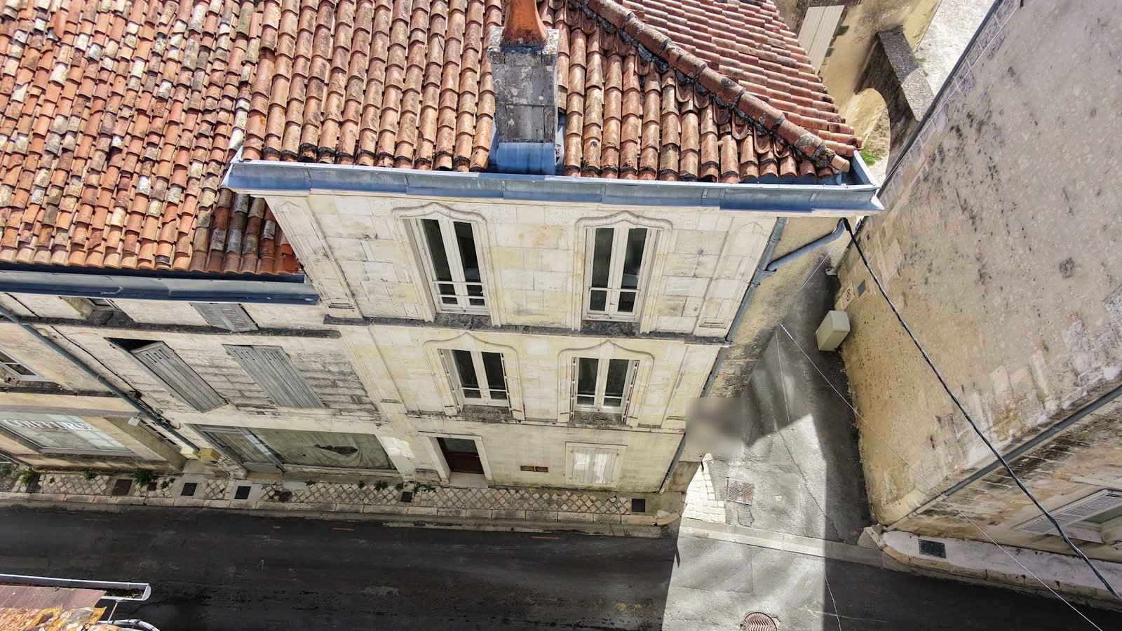 Vue a&eacute;rienne par drone d'une fa&ccedil;ade en pierre de taille, de sa toiture en tuiles canal et de sa souche de chemin&eacute;e, le type de relev&eacute; utilis&eacute; pour rep&eacute;rer fissures et d&eacute;sordres en hauteur