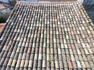 Vue aérienne verticale par drone d'une toiture en tuiles canal mêlant tuiles anciennes et tuiles neuves de remplacement, couverture saine prête pour un hydrofuge