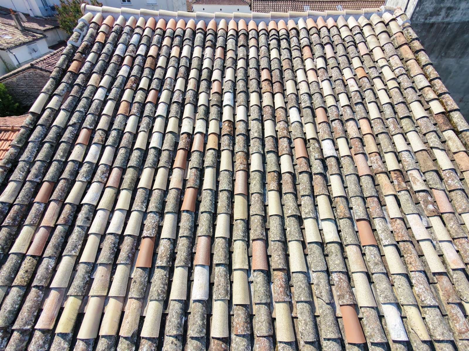 Vue a&eacute;rienne verticale par drone d'une toiture en tuiles canal m&ecirc;lant tuiles anciennes et tuiles neuves de remplacement, couverture saine pr&ecirc;te pour un hydrofuge